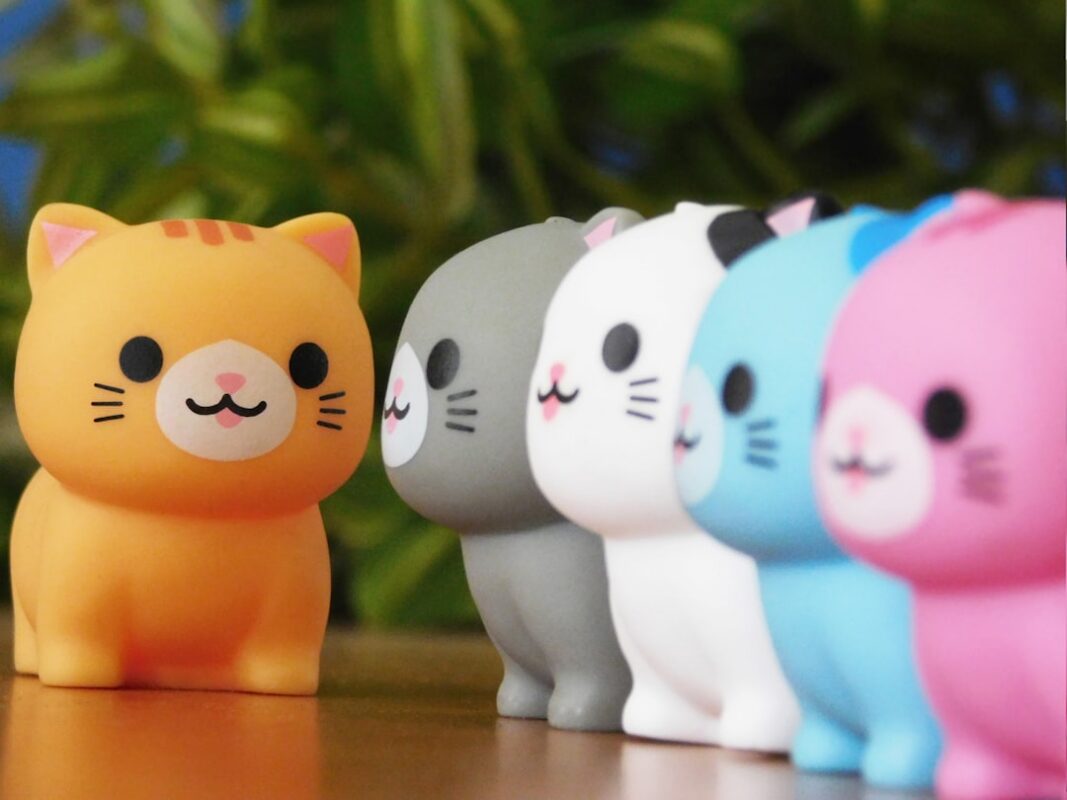 pet figurine - Row of colorful cat figurines with orange one in front