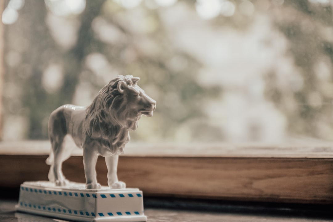 pet figurine - a white lion figurine sitting on top of a wooden table
